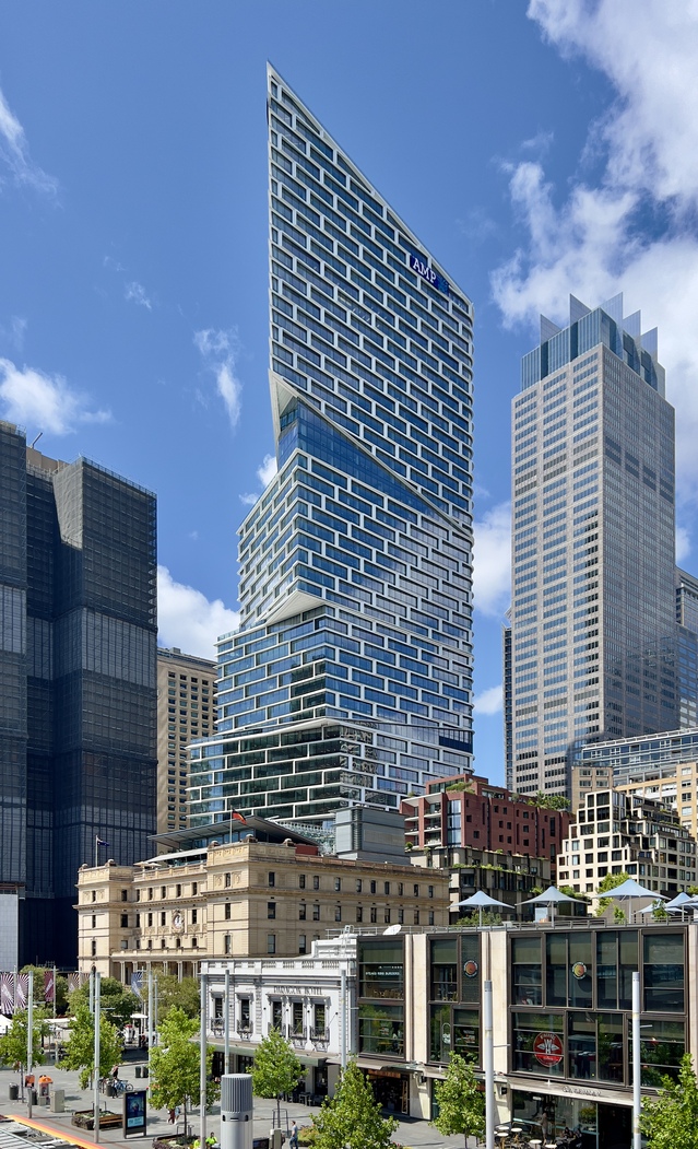 A tall skyscraper featuring stacked, angled glass blocks against a clear sky.