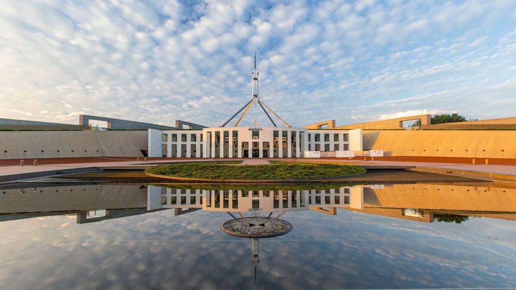 Australian Parliament House reflected in a large pool of water.