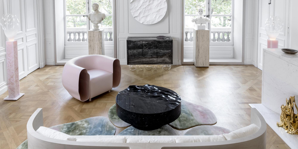 Avant-garde living space featuring sculptural furniture, a black ripple-textured coffee table, pastel rugs, and bust sculptures on plinths, best interior designers in Paris
