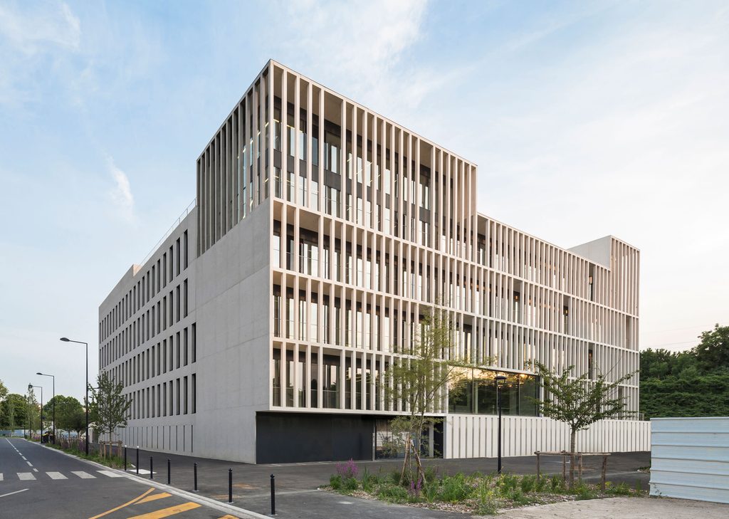 Exterior view of a modern multi-story concrete building featuring a distinct vertical slatted facade and wide windows. top interior design firms in milan