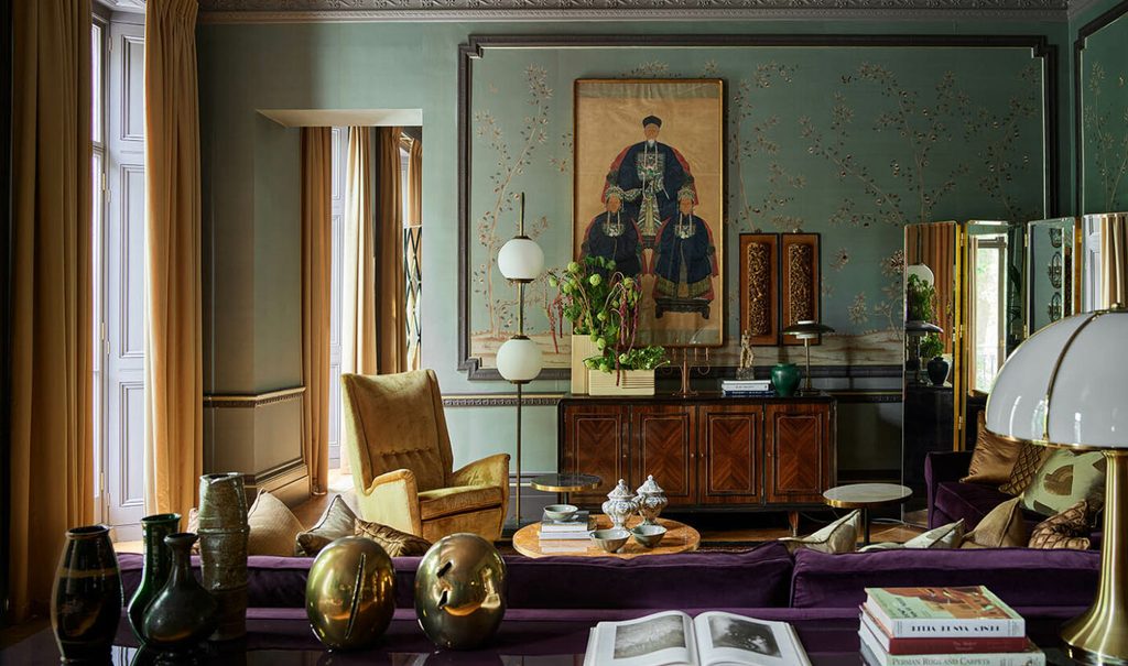 Eclectic, retro-inspired living room with sage green textured walls, a purple sofa, mustard armchair, and traditional Asian art. top interior design firms in milan